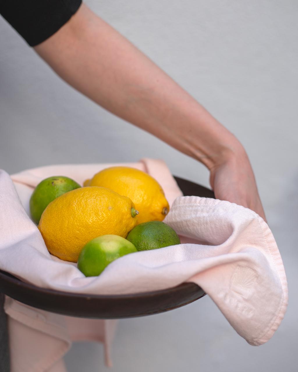 Person med citrusfrugter og et lyst køkkenhåndklæde.